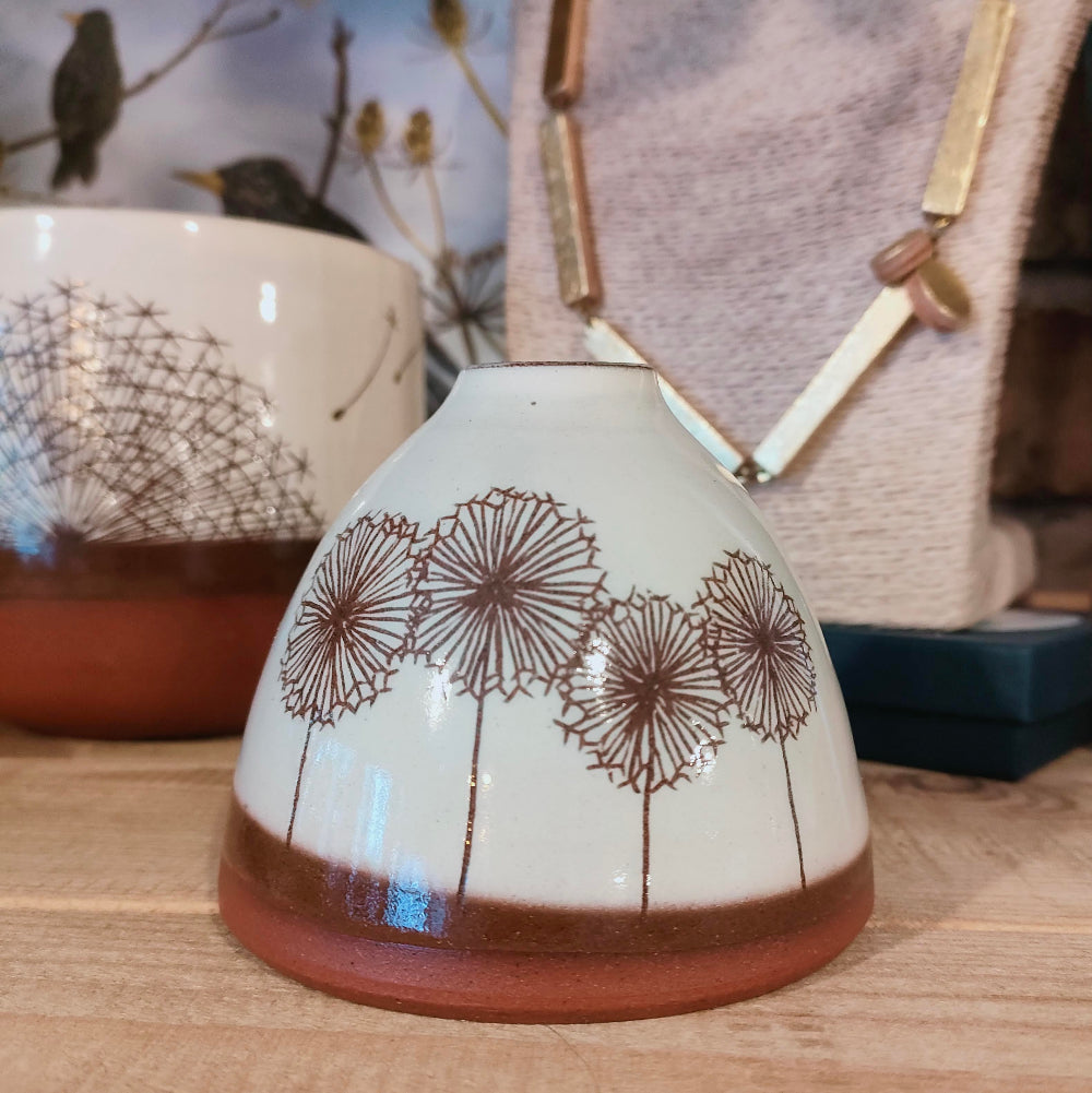Ceramic vase with dandelion design on a wooden surface