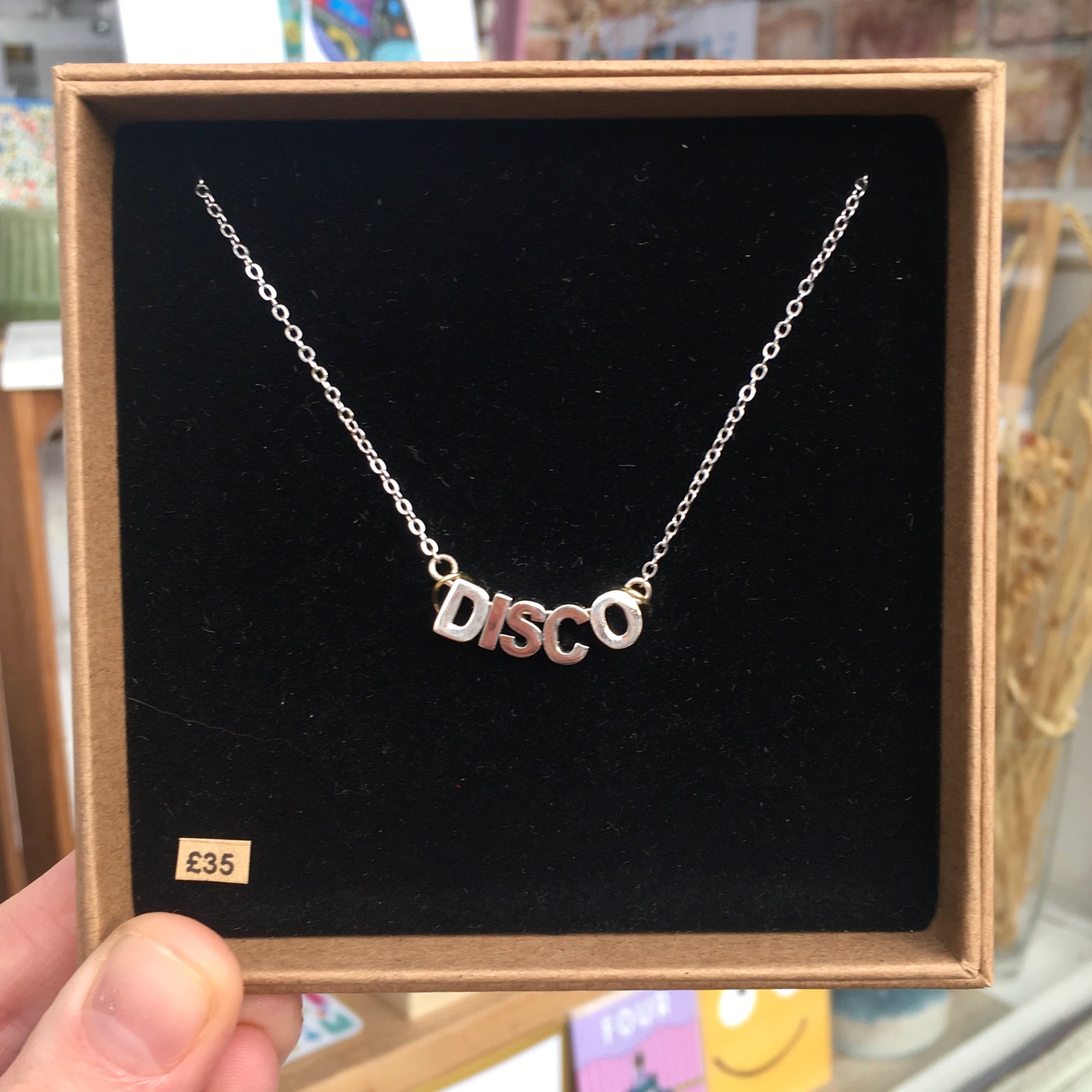 Three variations of a disco necklace with matt gold plated letters on adjustable chains.